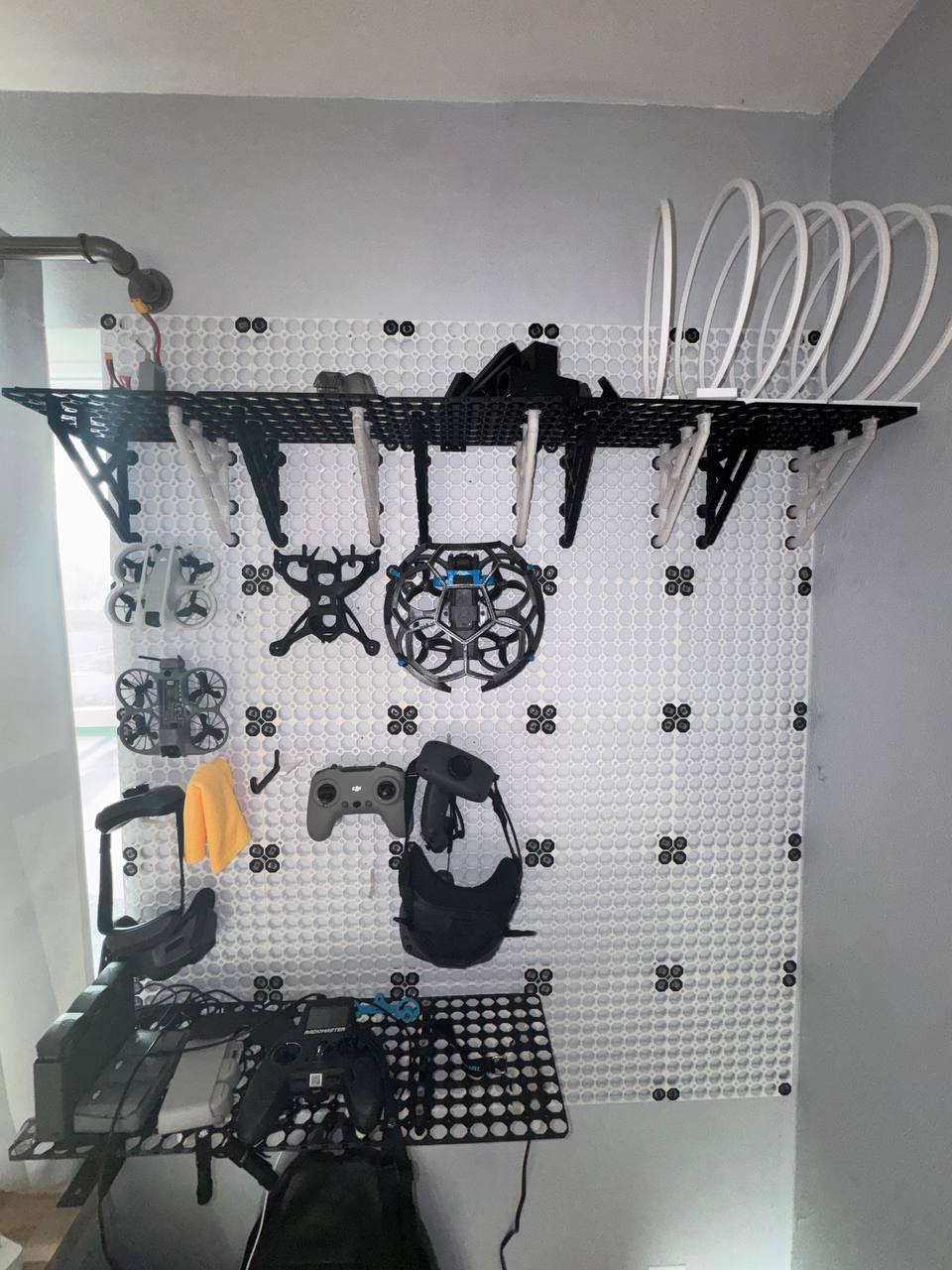 FPV drone wall — frames, goggles, controllers, and 3D printed parts